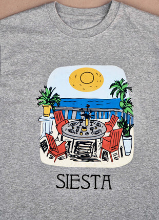 T-shirt Siesta Lunch Unisex Relaxed FitThis T-shirt impresses with its unique design depicting the Siesta process: a table set with traditional Spanish dishes against the backdrop of the picturesque sea. Made of 100% organic cotton, it is not only comfort